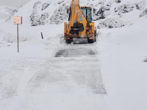 A snow plough clearing a snowy road.