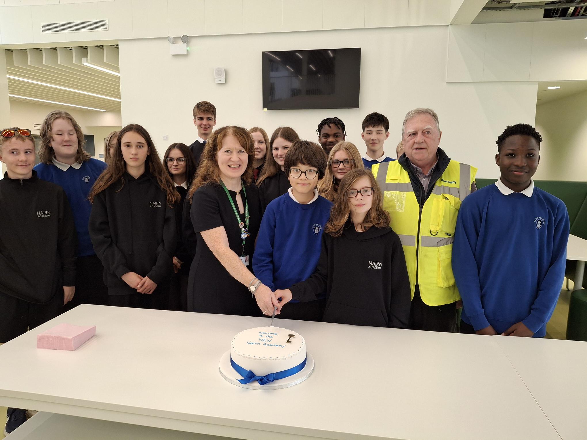 Nairn Academy head teacher Julie Macdonald joined by pupils and Jim McCluskie, Project Manager, Balfour Beatty to cut the cake to mark the school handover